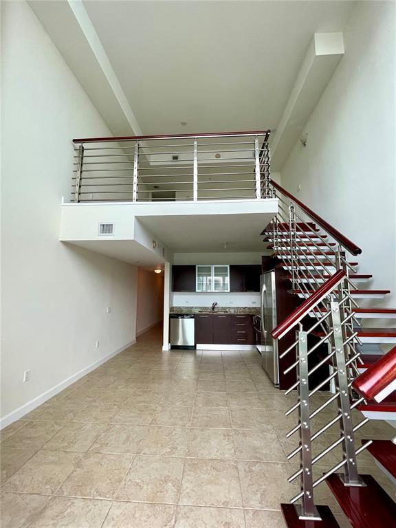 A lofted apartment interior features a kitchen, tile flooring, and a staircase with metal railings — 41 SE 5th Street # 1615, Miami FL 33131, MIAMI, FL