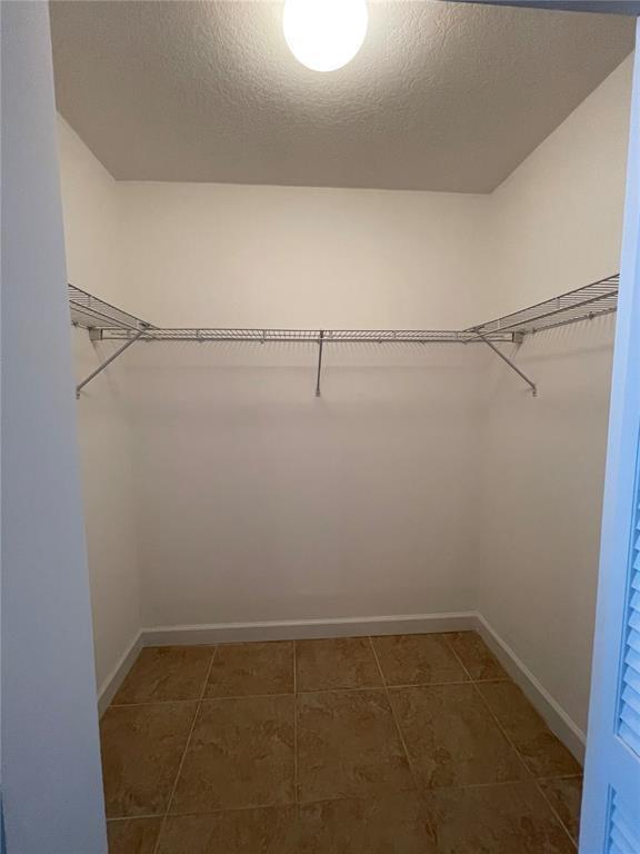 A walk-in closet features wire shelving, white walls, and tan tile flooring — 41 SE 5th Street # 1615, Miami FL 33131, MIAMI, FL