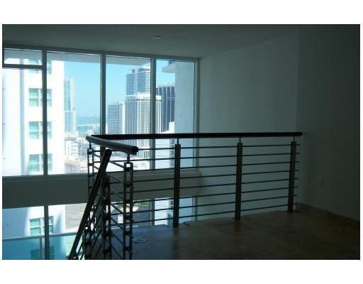 A loft area features a metal railing overlooking a room with floor-to-ceiling city view windows — 41 SE 5th Street # 1615, Miami FL 33131, MIAMI, FL