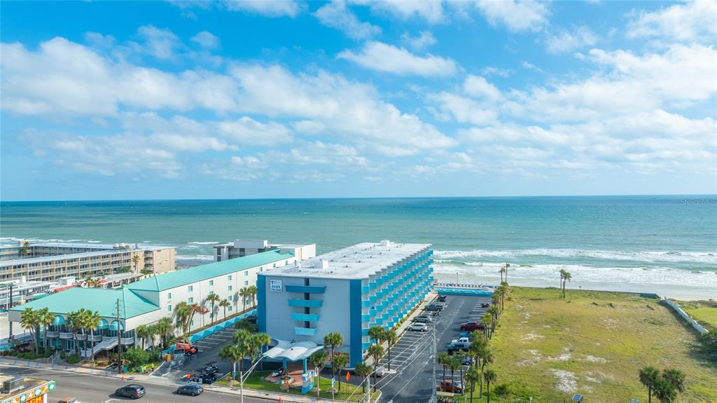 An aerial view shows a multi-story hotel building situated along a sandy beach and ocean — 313 S ATLANTIC AVENUE UNIT 4110, DAYTONA BEACH, FL