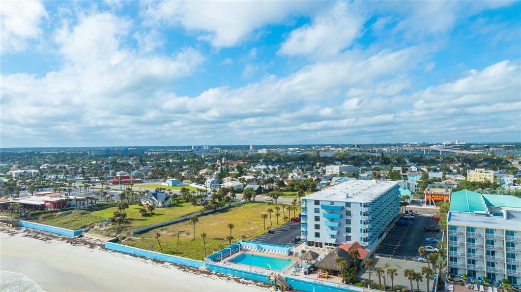 An aerial view shows a beachfront hotel with a pool, parking lot, and surrounding town — 313 S ATLANTIC AVENUE UNIT 4110, DAYTONA BEACH, FL