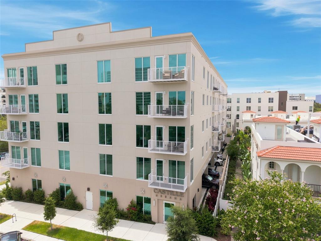 A multi-story apartment building with white balconies and large windows stands under a blue sky — 600 3RD AVENUE S UNIT 302, ST PETERSBURG, FL