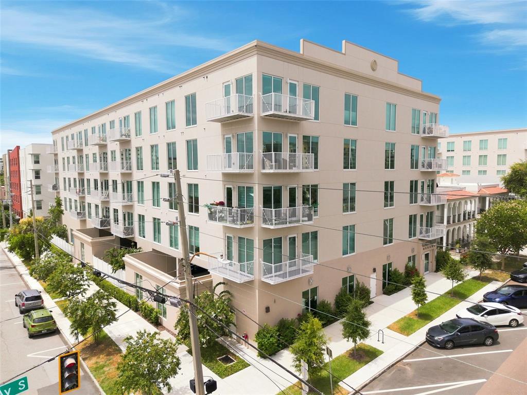 A multi-story apartment building with white balconies and large windows sits on a street corner — 600 3RD AVENUE S UNIT 302, ST PETERSBURG, FL