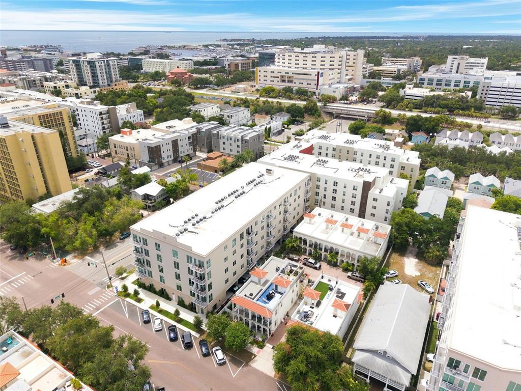 An aerial view shows a multi-story apartment complex surrounded by urban buildings and green trees — 600 3RD AVENUE S UNIT 302, ST PETERSBURG, FL