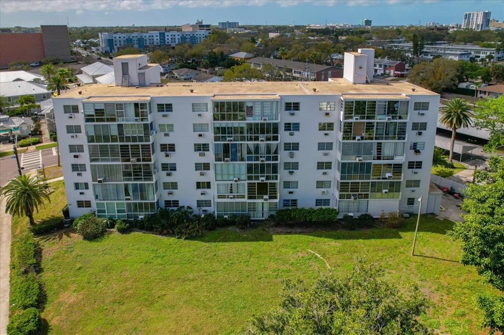 An aerial view of a multi-story white apartment building with balconies and a grassy lawn — 200 N BETTY LANE UNIT 1C, CLEARWATER, FL