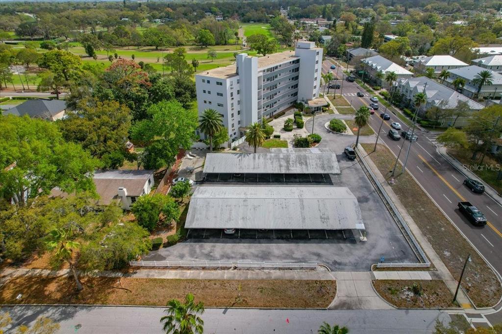 An aerial view shows a multi-story apartment building with two covered parking structures nearby — 200 N BETTY LANE UNIT 1C, CLEARWATER, FL