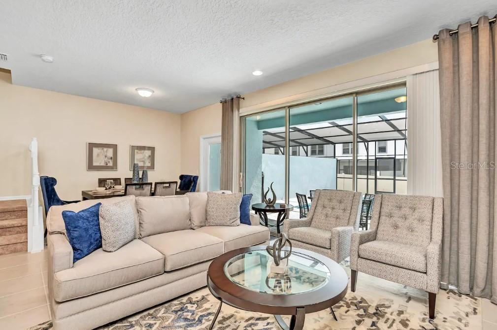 A living room features a beige sofa, two patterned armchairs, and a glass-topped coffee table — 2407 DUBAI STREET, KISSIMMEE, FL