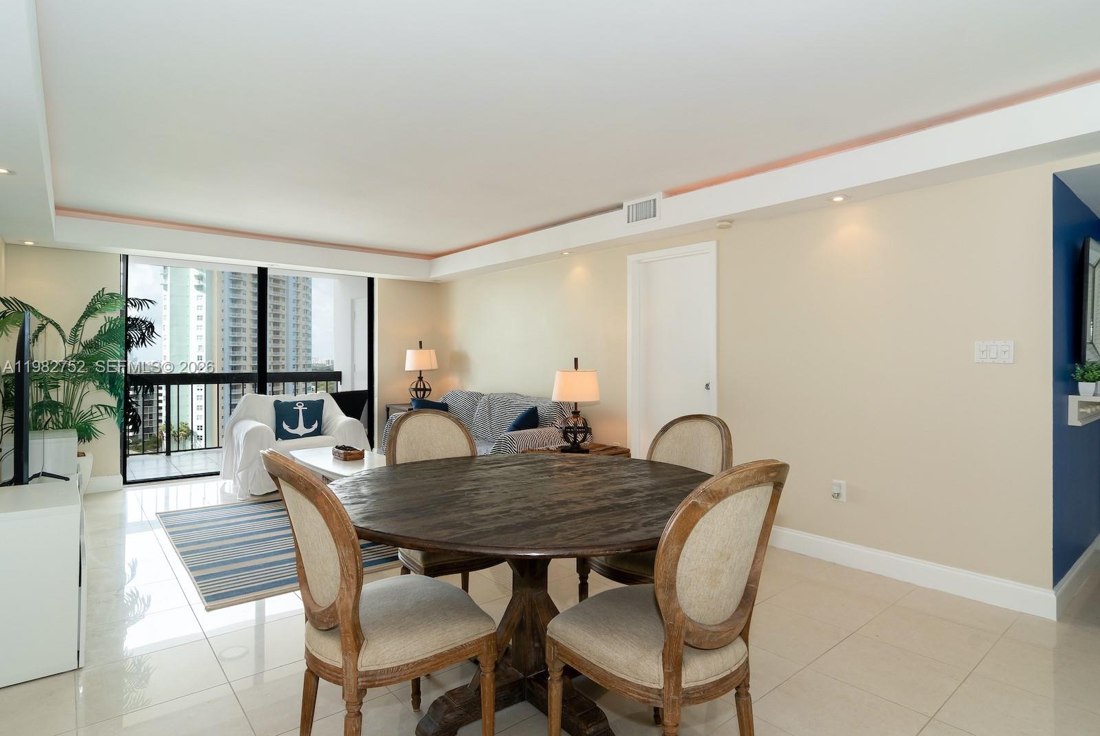 A dining area with a round wooden table and chairs overlooks a living room balcony — 2333 Brickell Ave # 1710, Miami FL 33129, MIAMI, FL