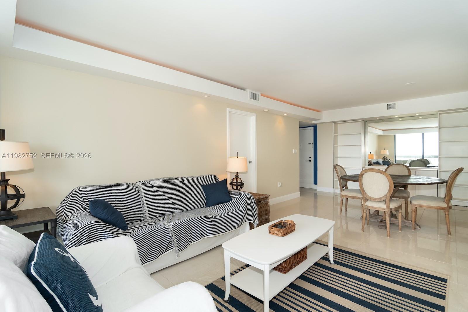 A living room with a striped sofa, white coffee table, and a dining area nearby — 2333 Brickell Ave # 1710, Miami FL 33129, MIAMI, FL