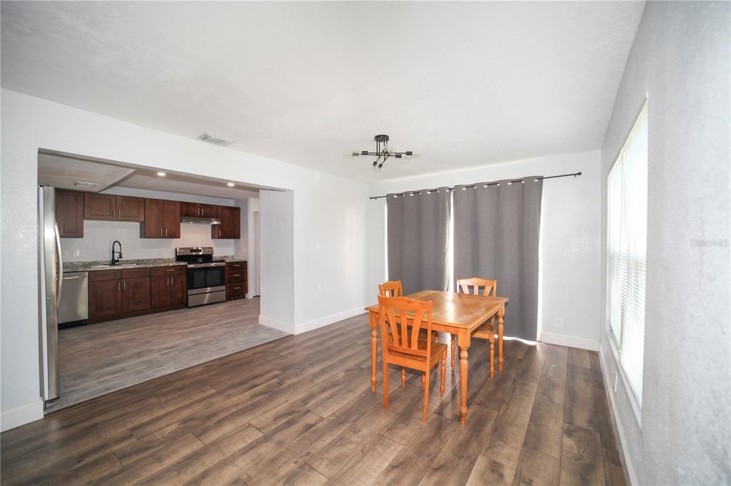 A dining area with wood-look flooring opens into a kitchen featuring dark wood cabinets — 331 AMHERST AVENUE UNIT 56, SARASOTA, FL