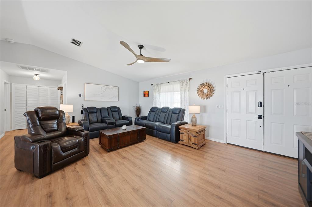 A living room features light wood flooring, dark leather furniture, and a vaulted ceiling — 515 GLEASON PARKWAY, CAPE CORAL, FL