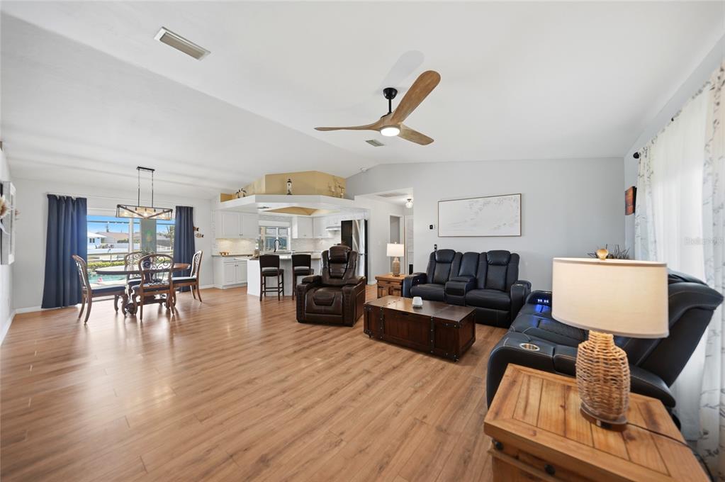An open-concept living and dining area features wood-look flooring, a ceiling fan, and white cabinets — 515 GLEASON PARKWAY, CAPE CORAL, FL