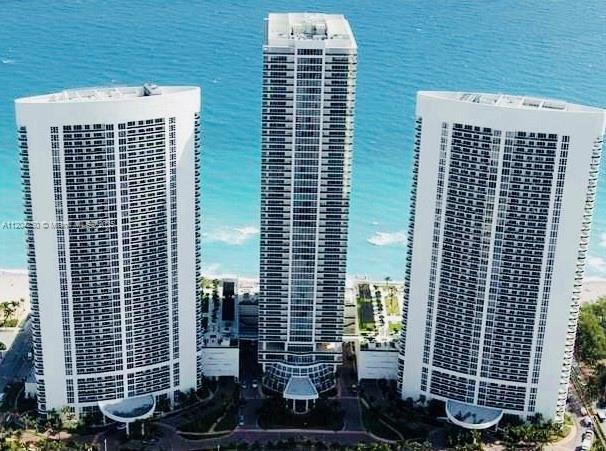 An aerial view shows three tall residential skyscrapers situated along a sandy beach and ocean — 1830 S Ocean Dr # 1709, Hallandale Beach FL 33009, HALLANDALE BEACH, FL