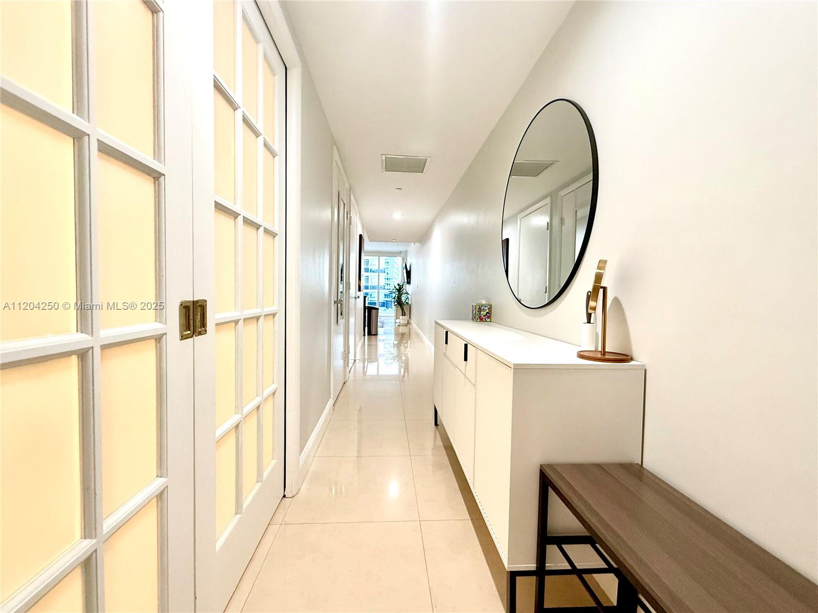 A bright hallway features white tile floors, a white console table, and a round mirror — 1830 S Ocean Dr # 1709, Hallandale Beach FL 33009, HALLANDALE BEACH, FL