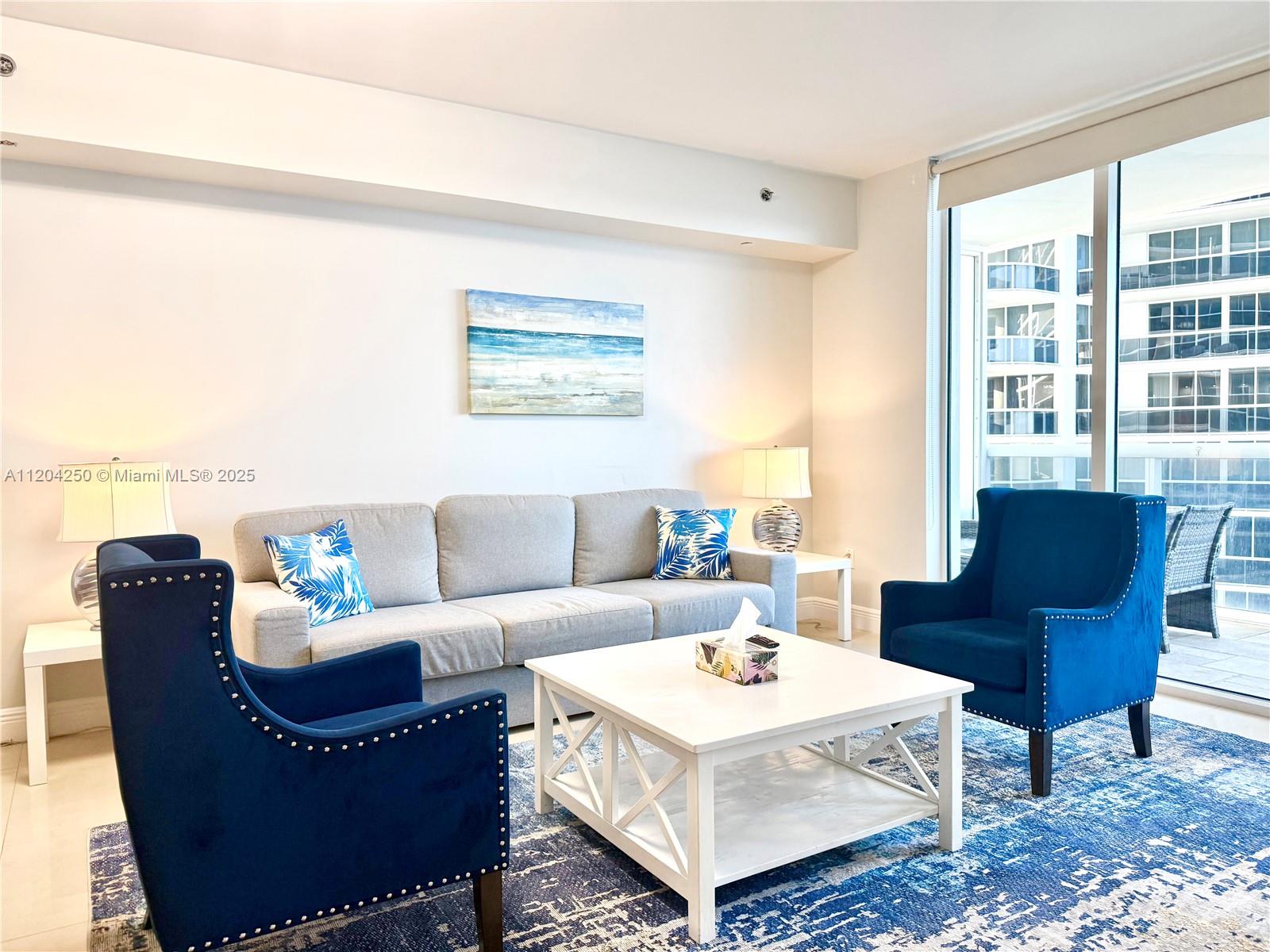 A living room features a grey sofa, two blue armchairs, and a white coffee table — 1830 S Ocean Dr # 1709, Hallandale Beach FL 33009, HALLANDALE BEACH, FL