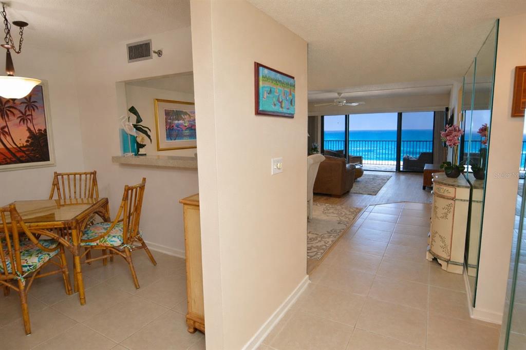 A dining area with bamboo furniture leads to a living room overlooking the ocean — 900 GULF BOULEVARD UNIT 907, INDIAN ROCKS BEACH, FL