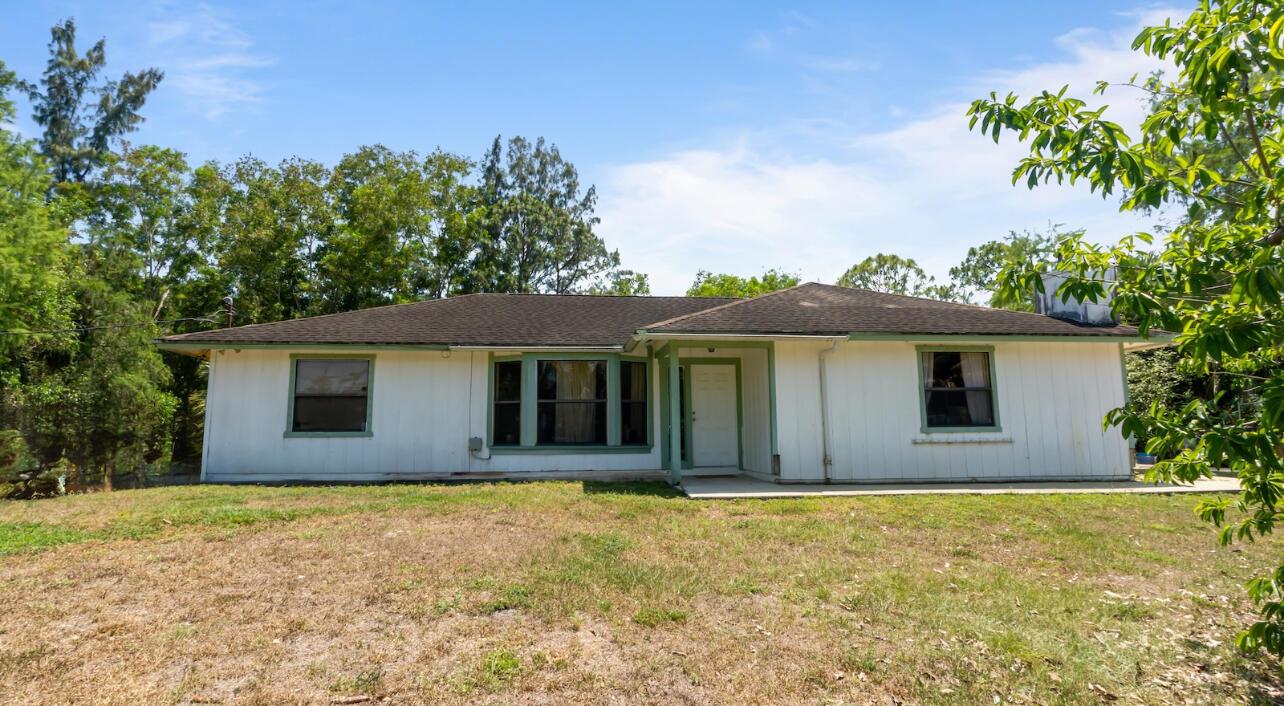 A single-story white house with a dark shingled roof and green trim sits on grass — 17254 32nd Lane N, FL 33470, FL