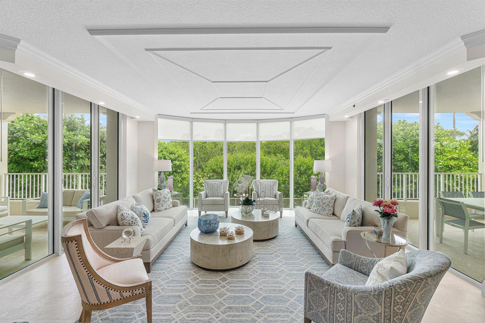 A bright living room features two sofas, patterned armchairs, round coffee tables, and floor-to-ceiling windows — 3720 S Ocean Boulevard # 208, Highland Beach FL 33487, HIGHLAND BEACH, FL