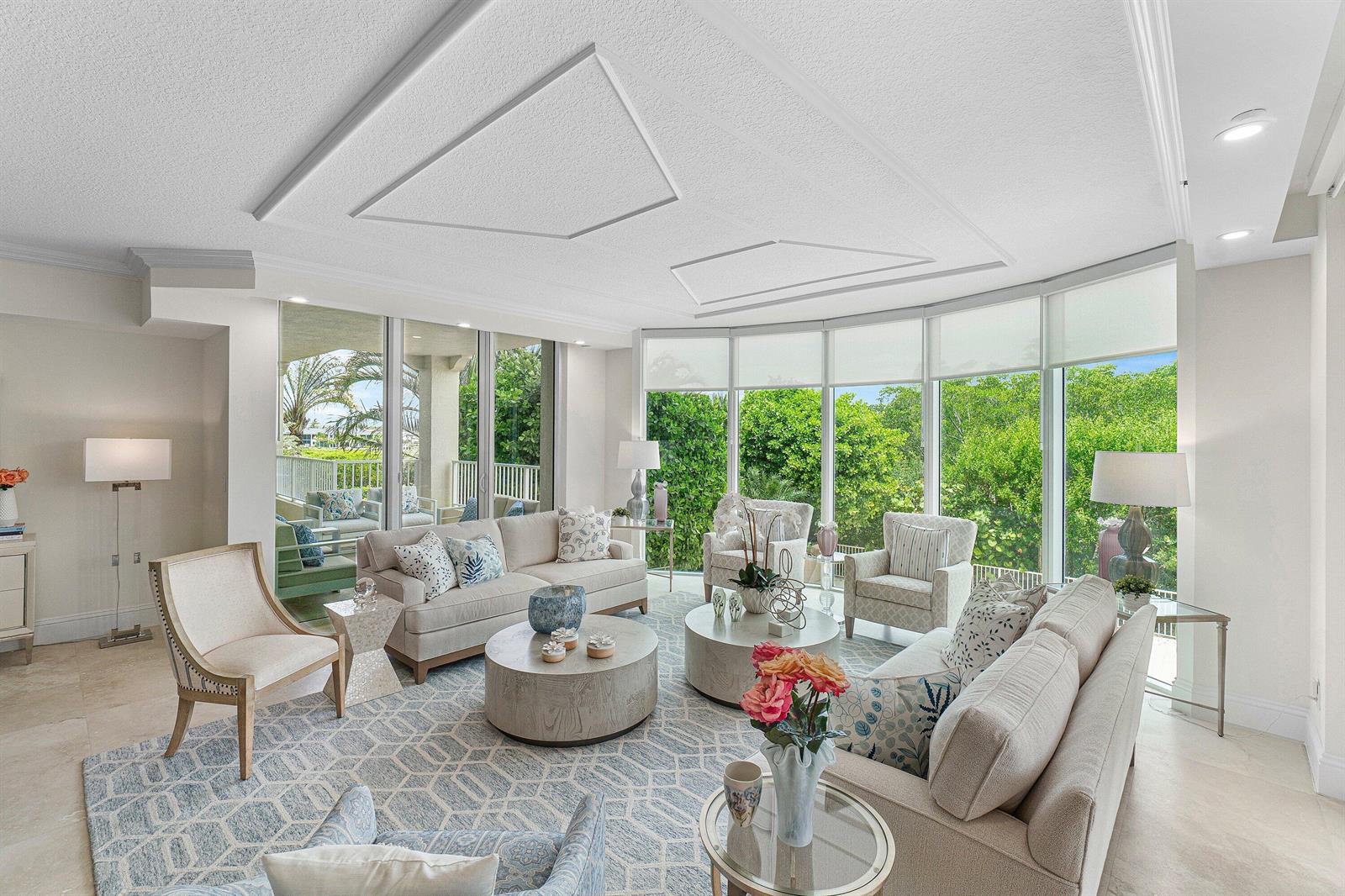 A bright living room features two beige sofas, round coffee tables, and floor-to-ceiling windows — 3720 S Ocean Boulevard # 208, Highland Beach FL 33487, HIGHLAND BEACH, FL