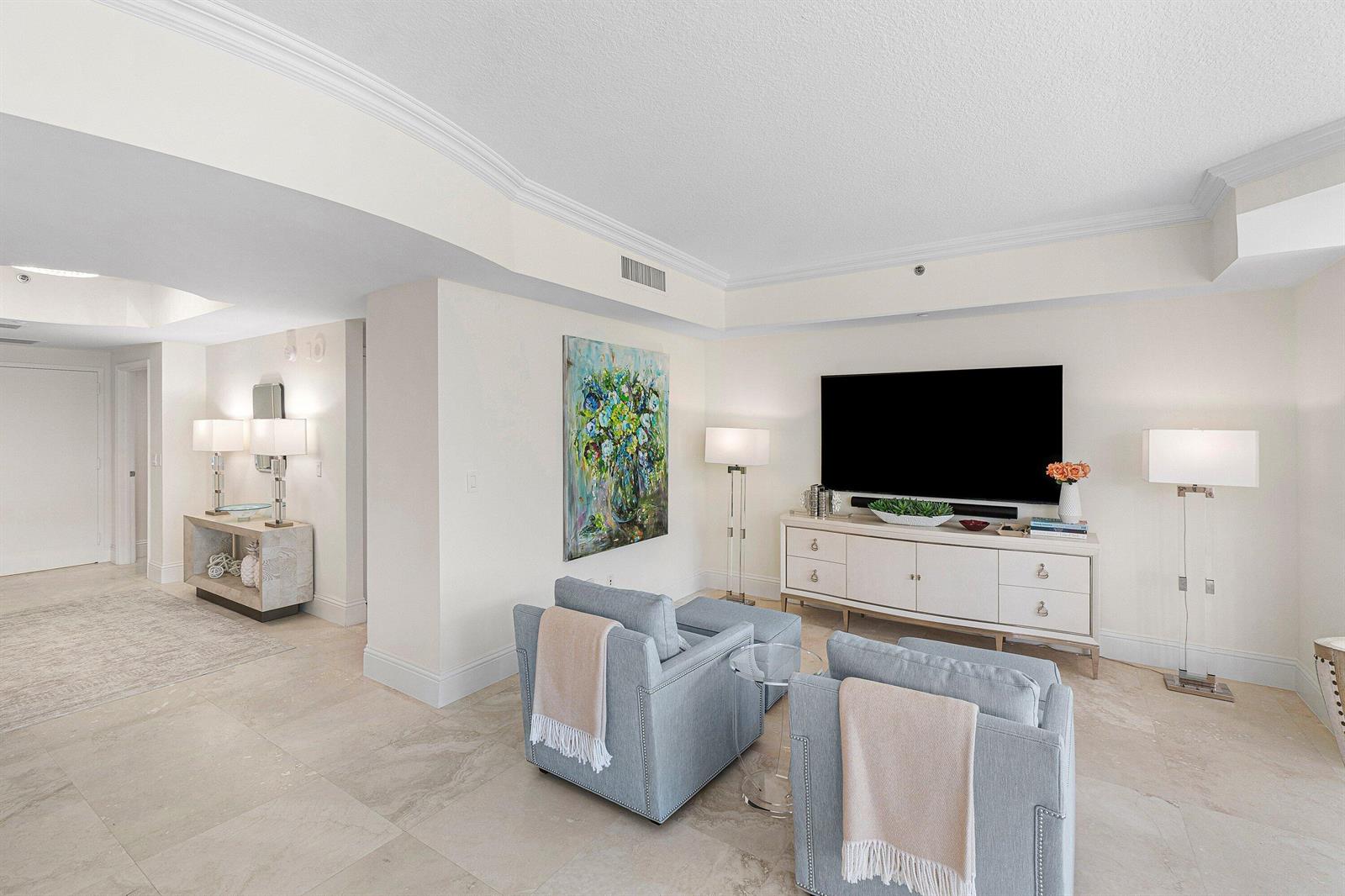A living room features two light blue armchairs, a white media console, and tile flooring — 3720 S Ocean Boulevard # 208, Highland Beach FL 33487, HIGHLAND BEACH, FL