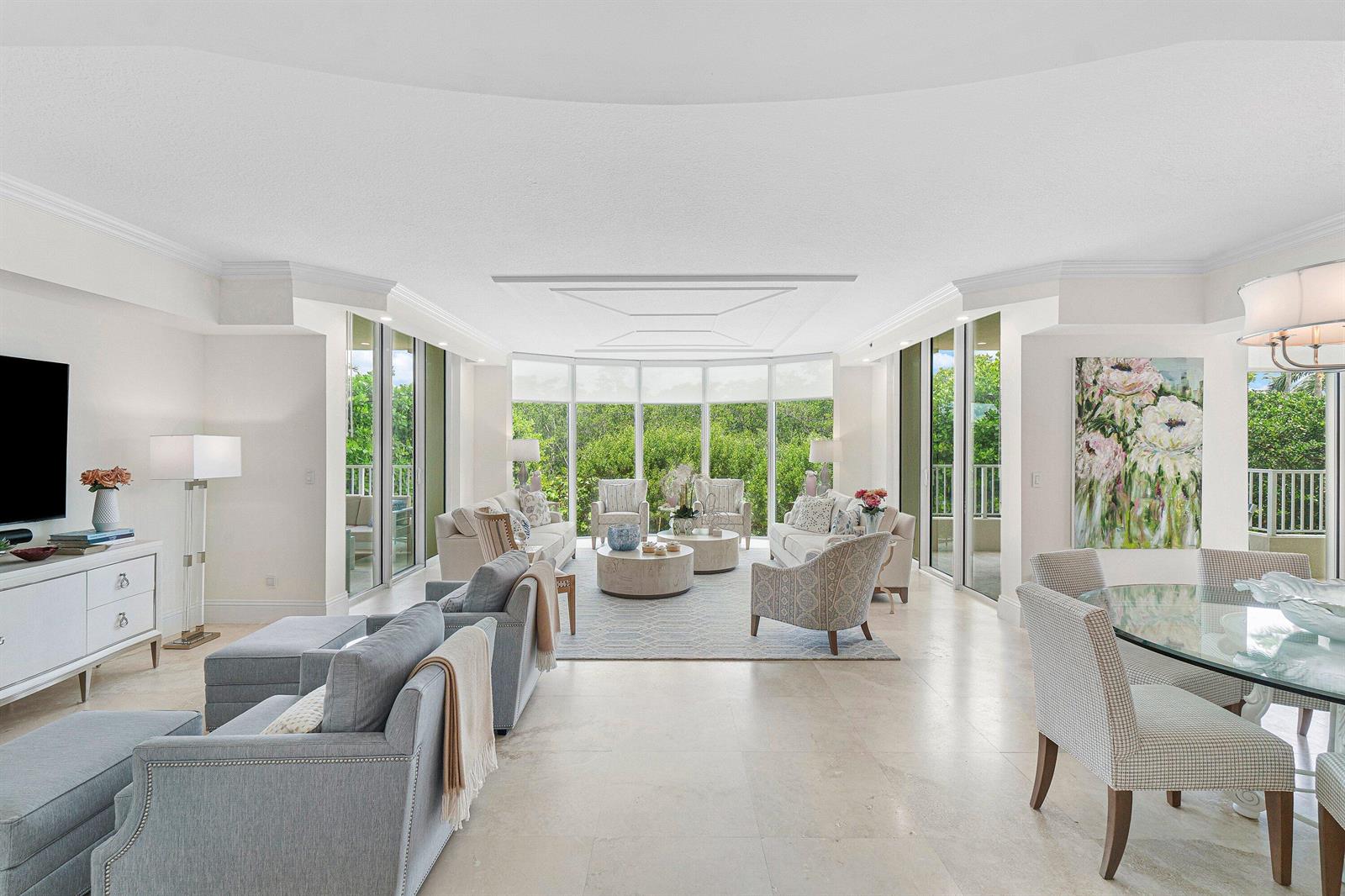 A bright, open-concept living and dining area features large windows overlooking lush green trees — 3720 S Ocean Boulevard # 208, Highland Beach FL 33487, HIGHLAND BEACH, FL