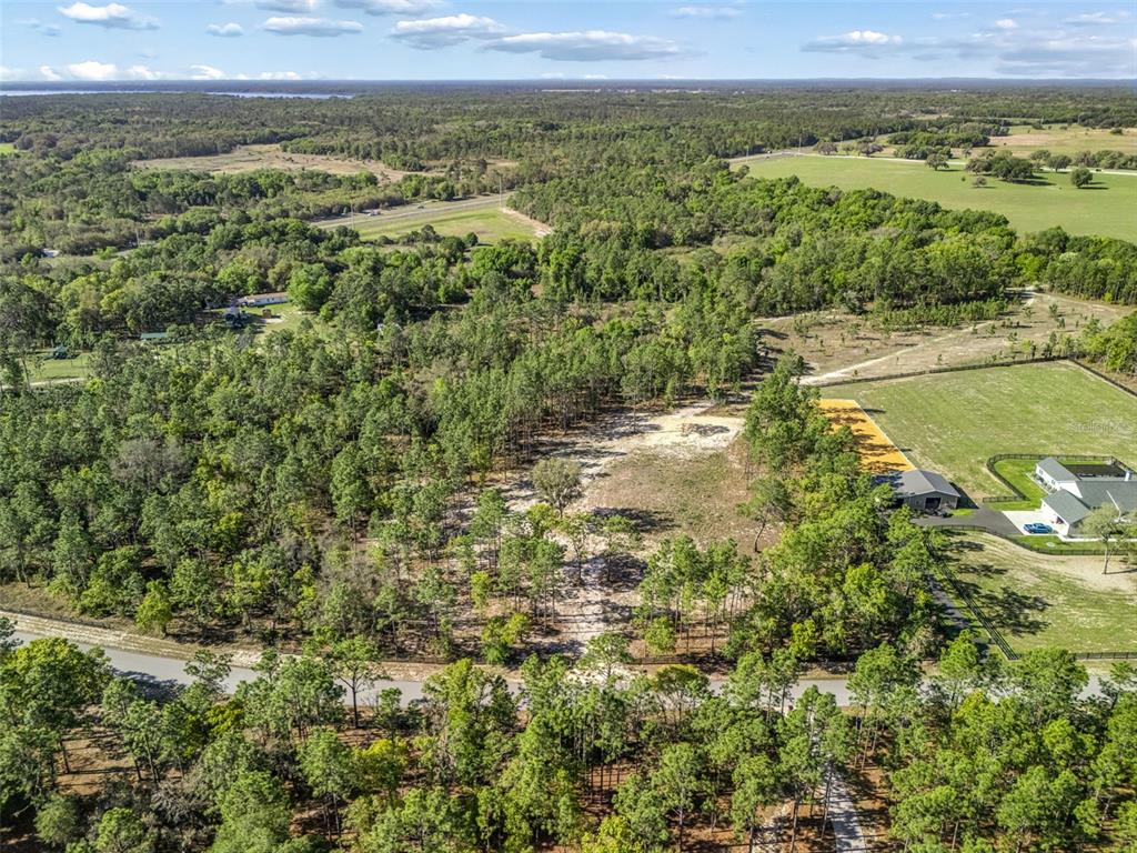 An aerial view shows a cleared, wooded lot adjacent to a house and fenced pasture — 2395 NW 81ST AVENUE, WILDWOOD, FL