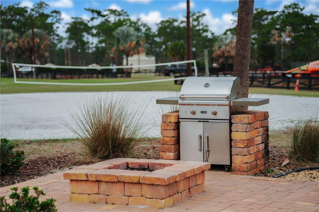 A stainless steel grill and a brick fire pit sit on a paved patio area — 0 HIGHWAY 630 E UNIT 7, LAKE WALES, FL