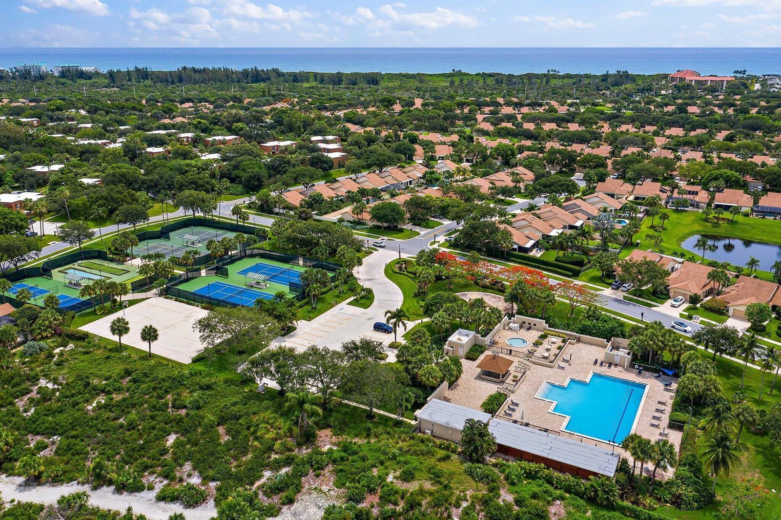 A two-story brown building with a wooden fence, palm trees, and lush landscaping — 2411 24th Court, Jupiter FL 33477, JUPITER, FL
