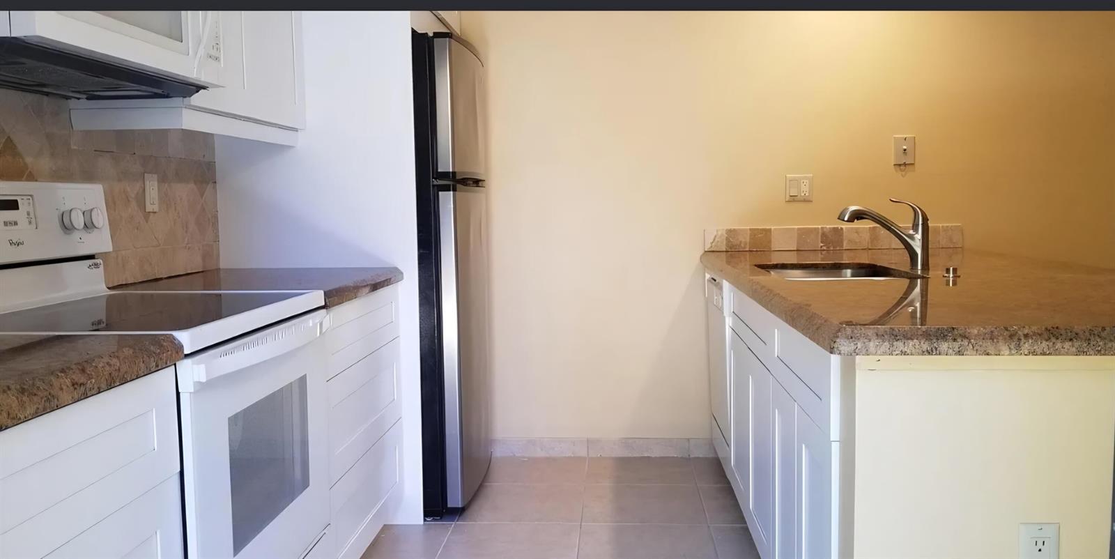 A kitchen features white cabinets, granite countertops, stainless steel appliances, and a breakfast bar — 2411 24th Court, Jupiter FL 33477, JUPITER, FL
