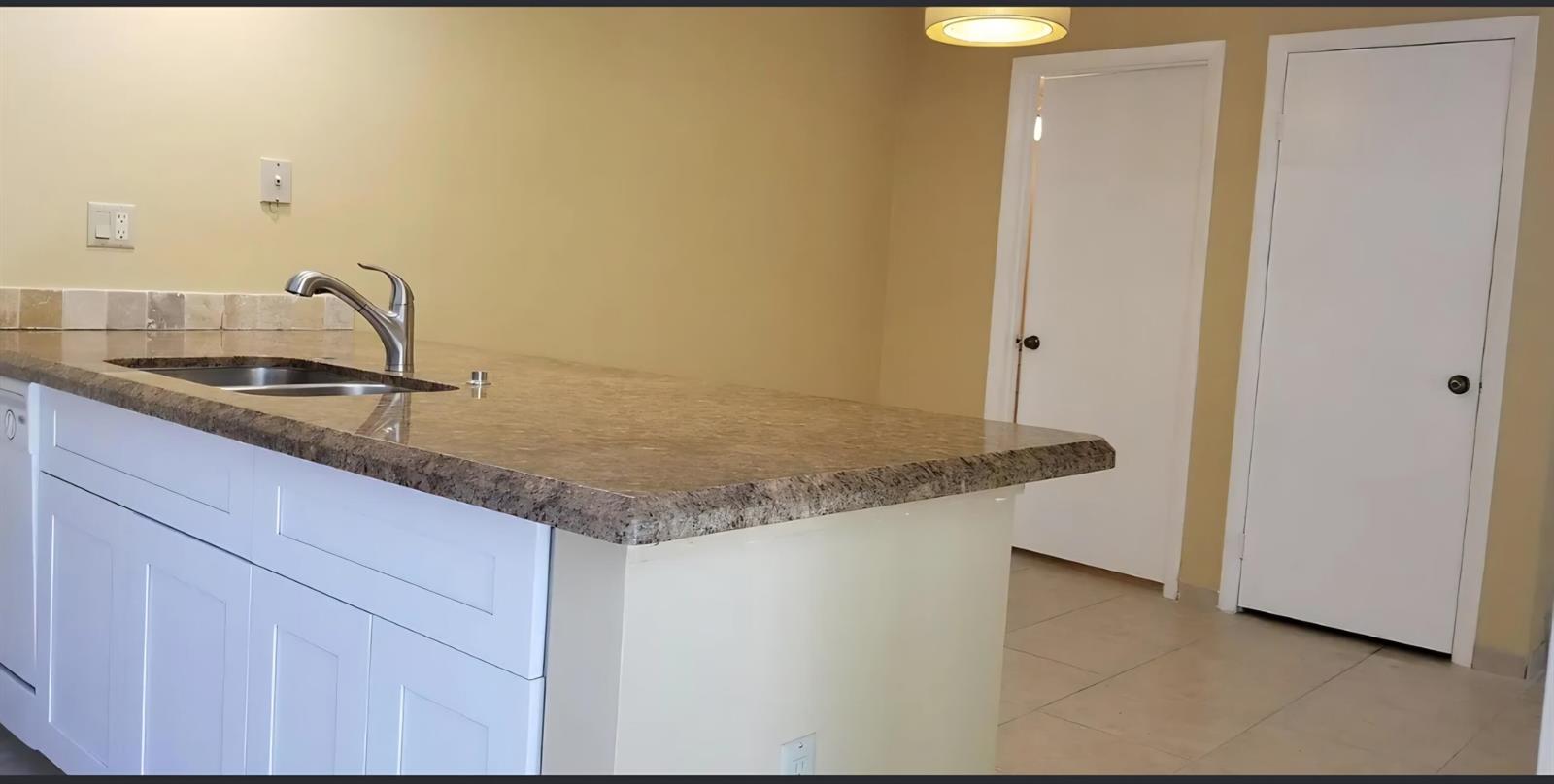 A kitchen features white cabinets, granite countertops, stainless steel appliances, and light-colored tile flooring — 2411 24th Court, Jupiter FL 33477, JUPITER, FL