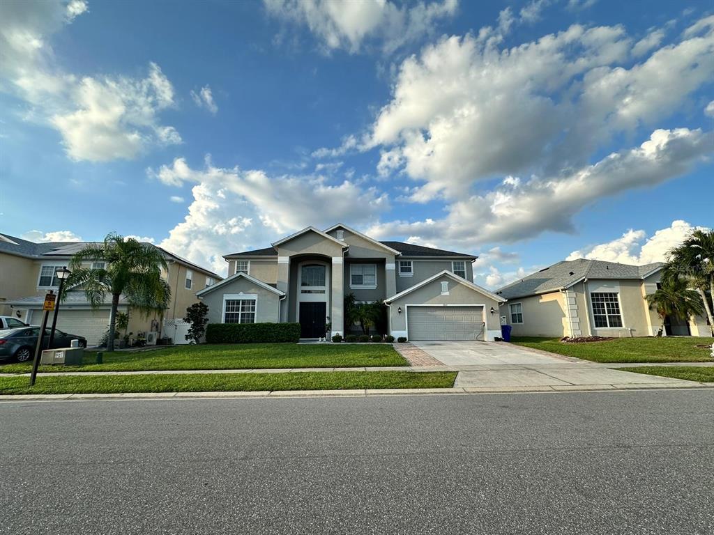 A two-story suburban house with a gray exterior, a two-car garage, and a manicured lawn — 2321 HINSDALE DRIVE, KISSIMMEE, FL