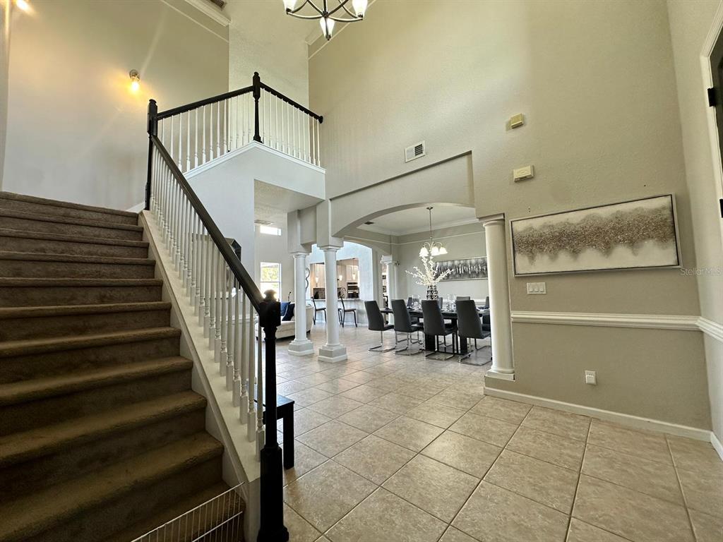 A two-story foyer features a carpeted staircase, tile flooring, and an open dining area beyond — 2321 HINSDALE DRIVE, KISSIMMEE, FL