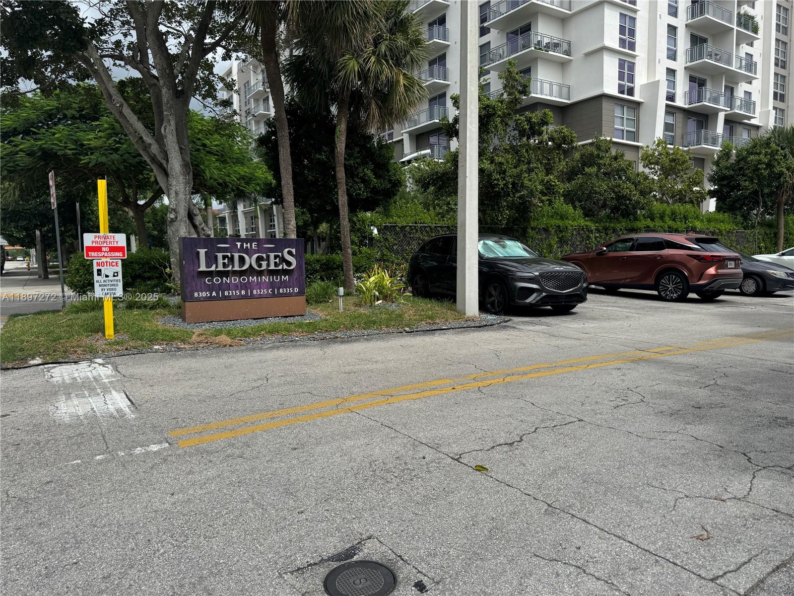 A sign for The Ledges Condominium stands near a parking lot with several parked cars — 8315 SW 72nd Ave # 101B, Miami FL 33143, MIAMI, FL