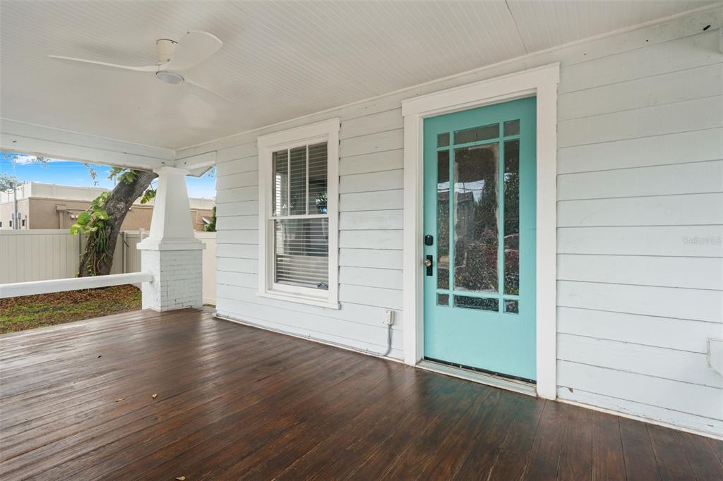 A covered porch features a dark wood floor, light blue siding, and a teal front door — 102 W NORTH STREET, TAMPA, FL