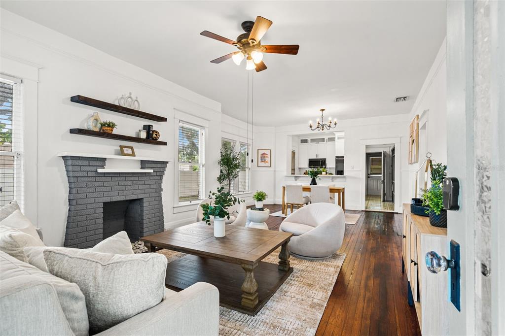 A living room with a gray brick fireplace, wood floors, and an open dining area — 102 W NORTH STREET, TAMPA, FL