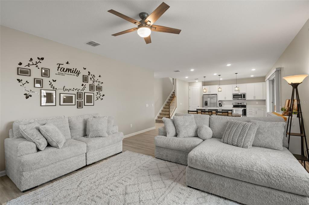 A living room with light gray furniture, a white rug, and an open kitchen area — 1542 SUGARBELLE CIRCLE, MASCOTTE, FL