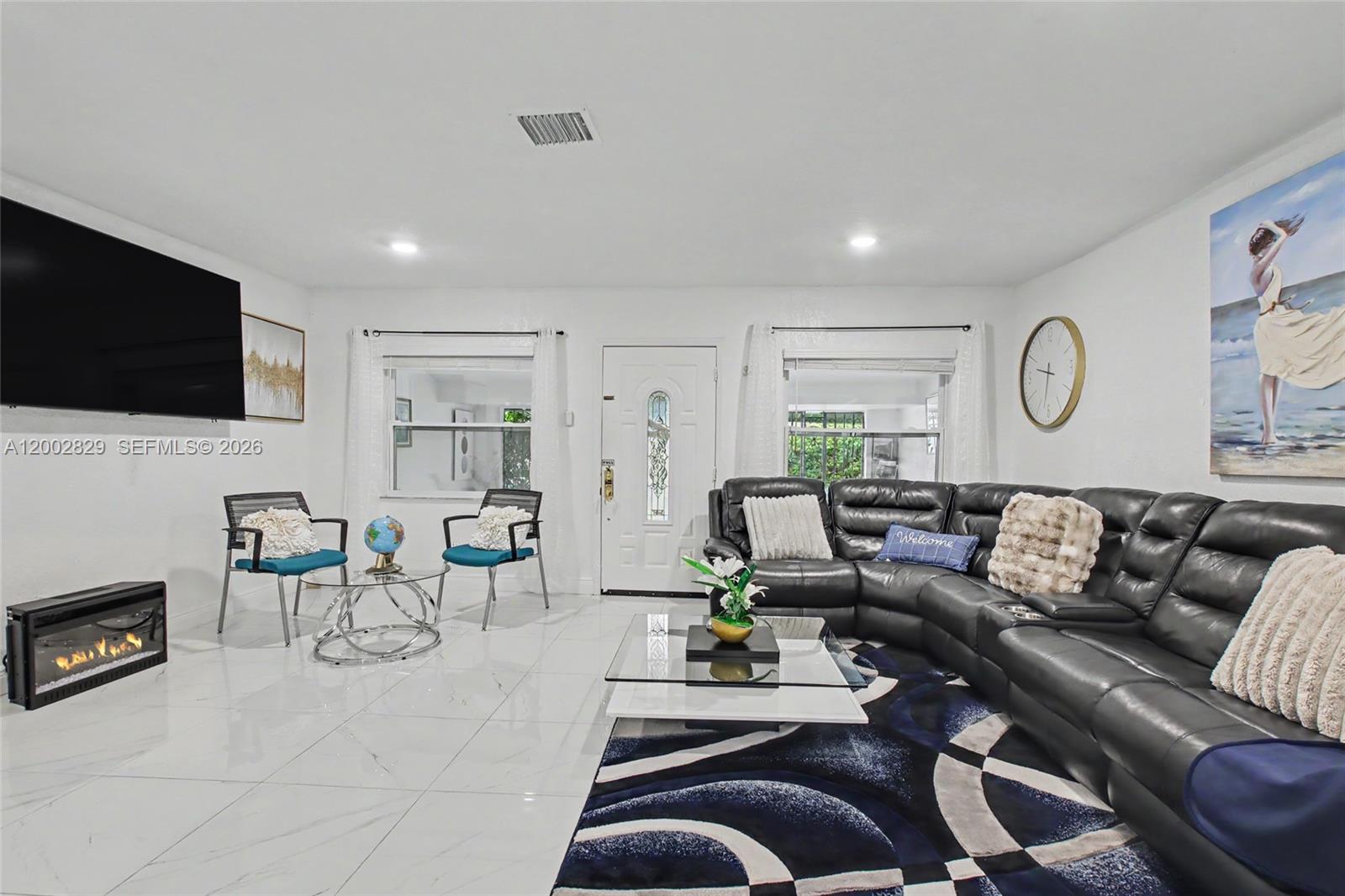 A living room features white tile floors, a black leather sectional, and a wall-mounted television — 2145 NW 133rd St # 2145, Miami FL 33167, MIAMI, FL