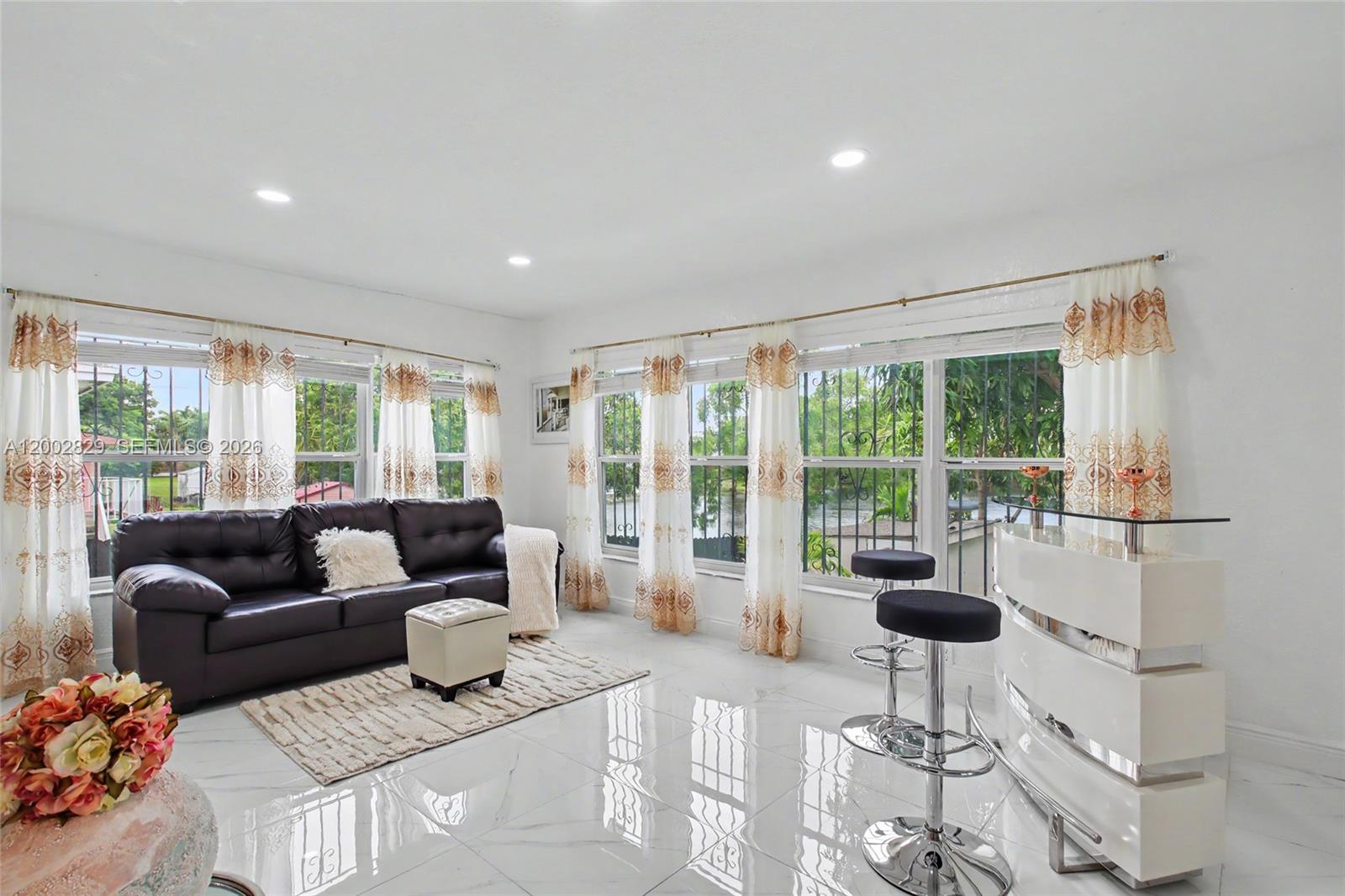 A living room features white tile floors, a dark leather sofa, and a glass-topped bar — 2145 NW 133rd St # 2145, Miami FL 33167, MIAMI, FL