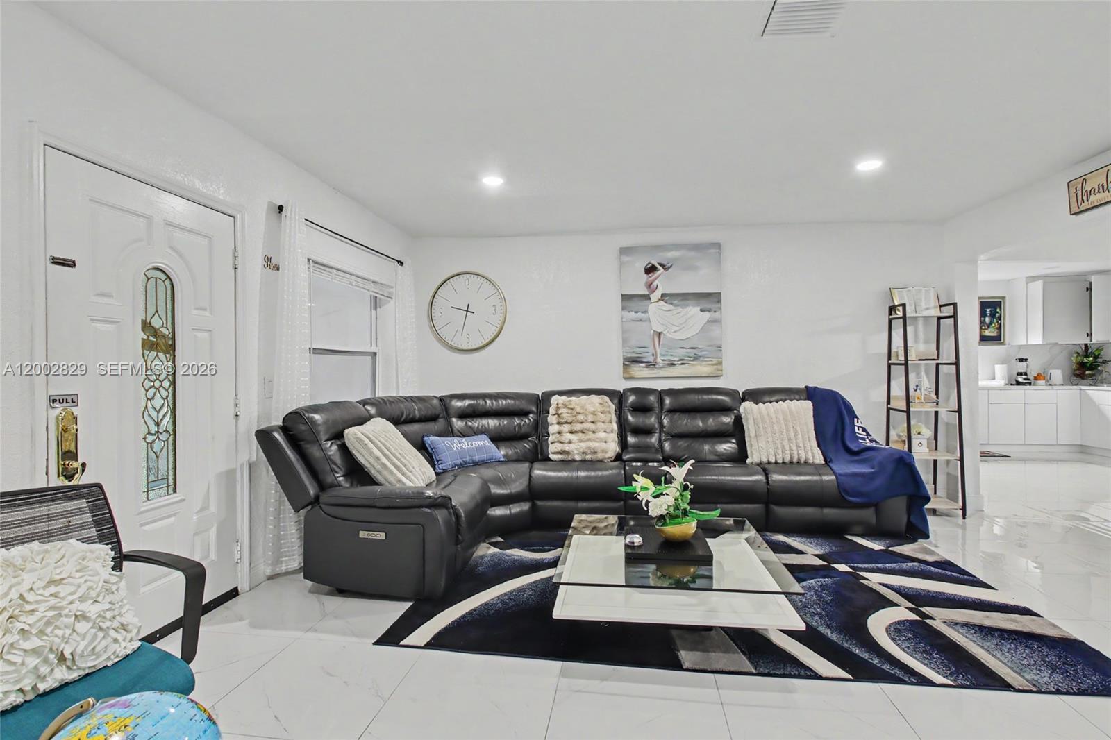 A living room features a black sectional sofa, a glass coffee table, and white tile flooring — 2145 NW 133rd St # 2145, Miami FL 33167, MIAMI, FL