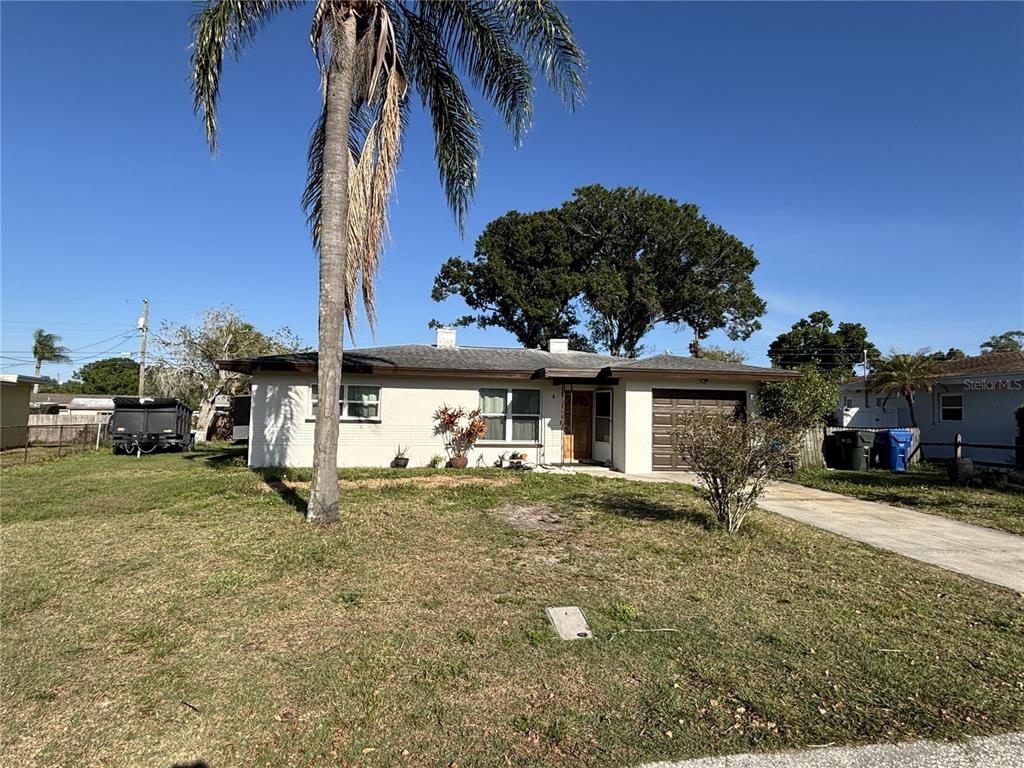 A single-story house with a palm tree, a front lawn, and an attached garage — 1347 BUCKINGHAM DRIVE, CLEARWATER, FL