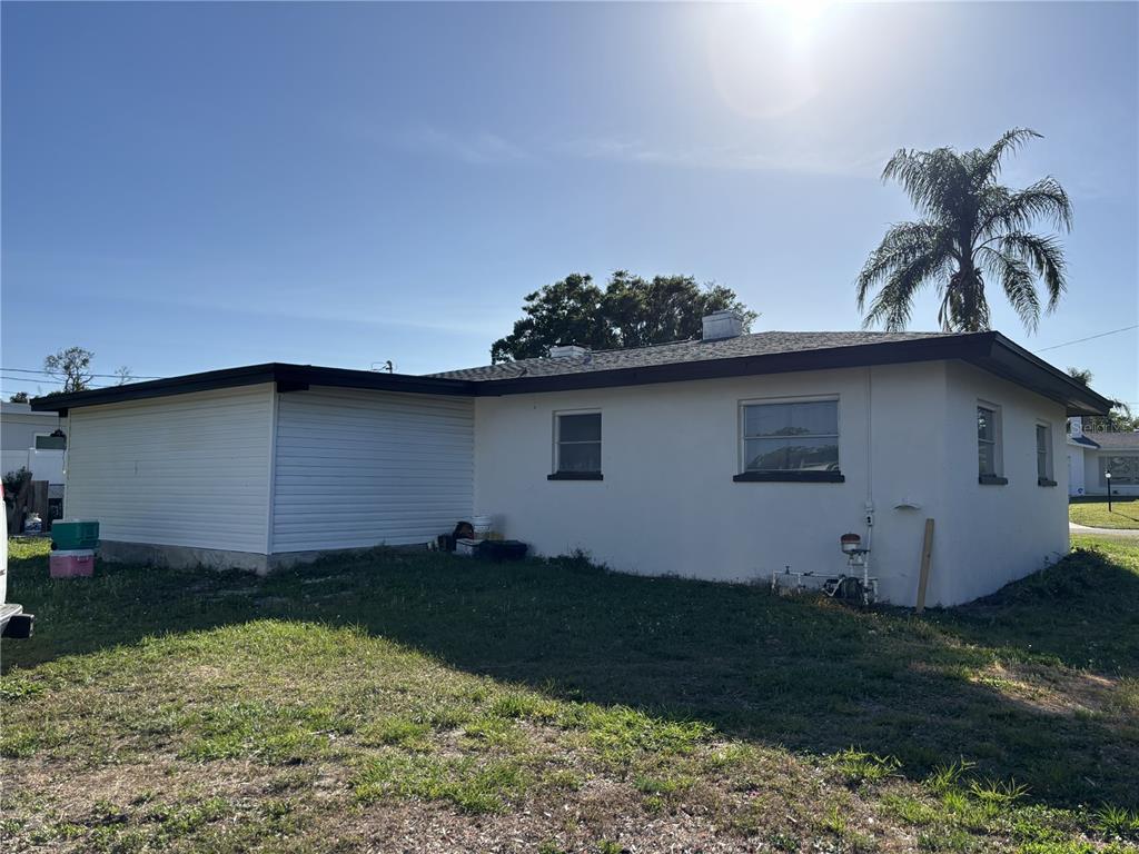 The exterior of a single-story house features white stucco walls, horizontal siding, and a palm tree — 1347 BUCKINGHAM DRIVE, CLEARWATER, FL