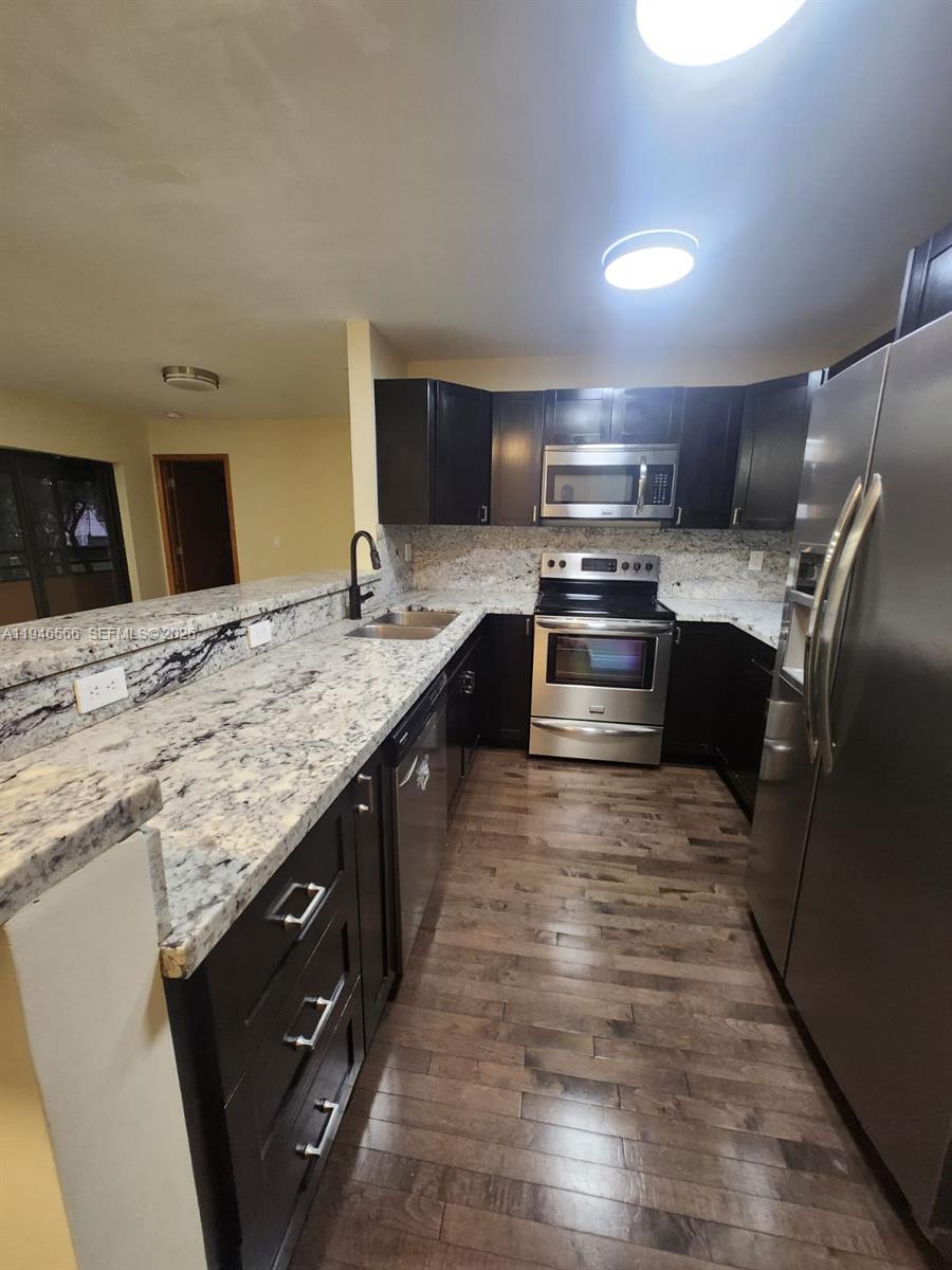 A kitchen features dark wood cabinets, granite countertops, stainless steel appliances, and wood-look flooring — 20005 NE 3rd Ct # 6, Miami FL 33179, MIAMI, FL