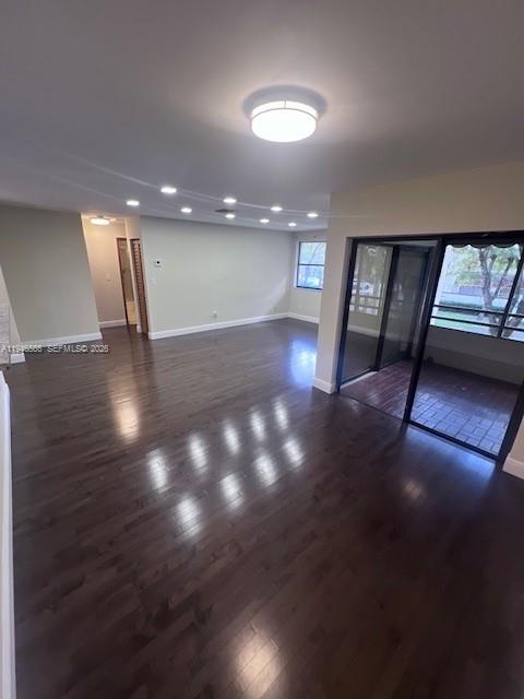 An empty living room features dark hardwood floors, recessed lighting, and sliding glass patio doors — 20005 NE 3rd Ct # 6, Miami FL 33179, MIAMI, FL