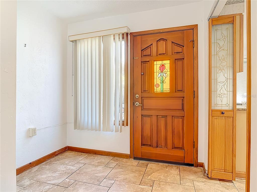 An entryway features a wood front door with a stained glass insert and tile flooring — 65 ELMWOOD TRAIL, DELAND, FL