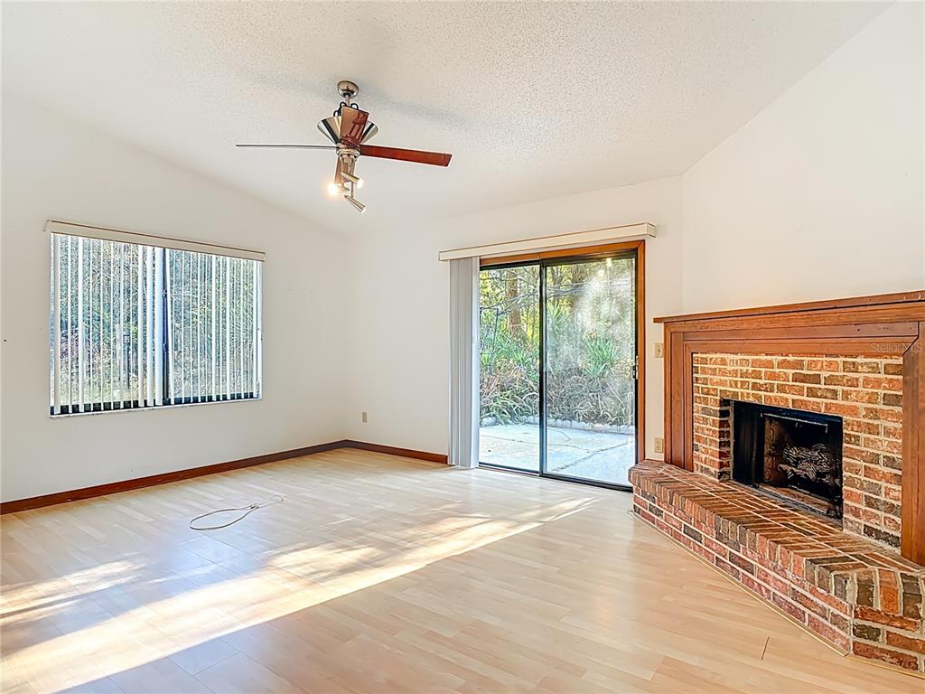 A living room features light wood flooring, a brick fireplace, and sliding glass patio doors — 65 ELMWOOD TRAIL, DELAND, FL