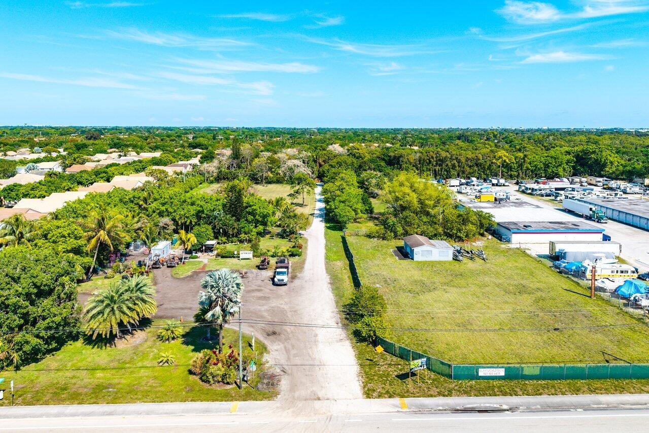 An aerial view shows a gravel driveway leading to a property with trees and buildings — 0 S Military Trail, Delray Beach FL 33415, DELRAY BEACH, FL