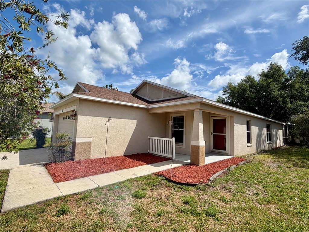 A single-story house with a tan stucco exterior, brown roof, and a red front door — 4316 OLD WAVERLY COURT, WESLEY CHAPEL, FL
