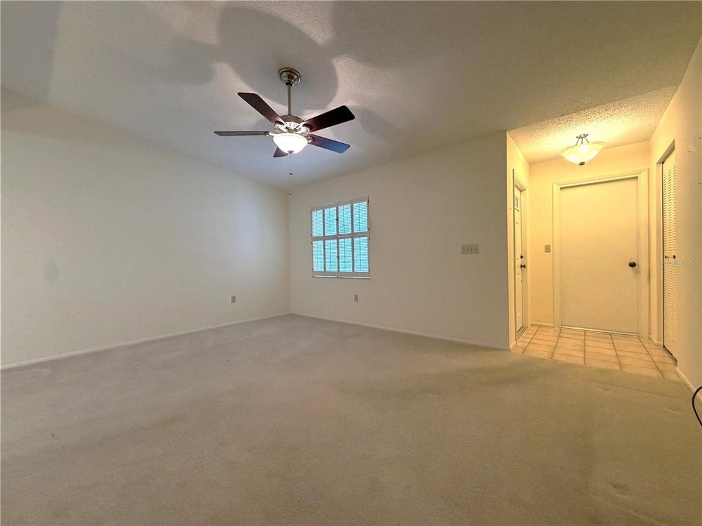 An empty room with beige carpeting, a ceiling fan, and an entryway with tiled flooring — 6736 JARVIS ROAD, SARASOTA, FL