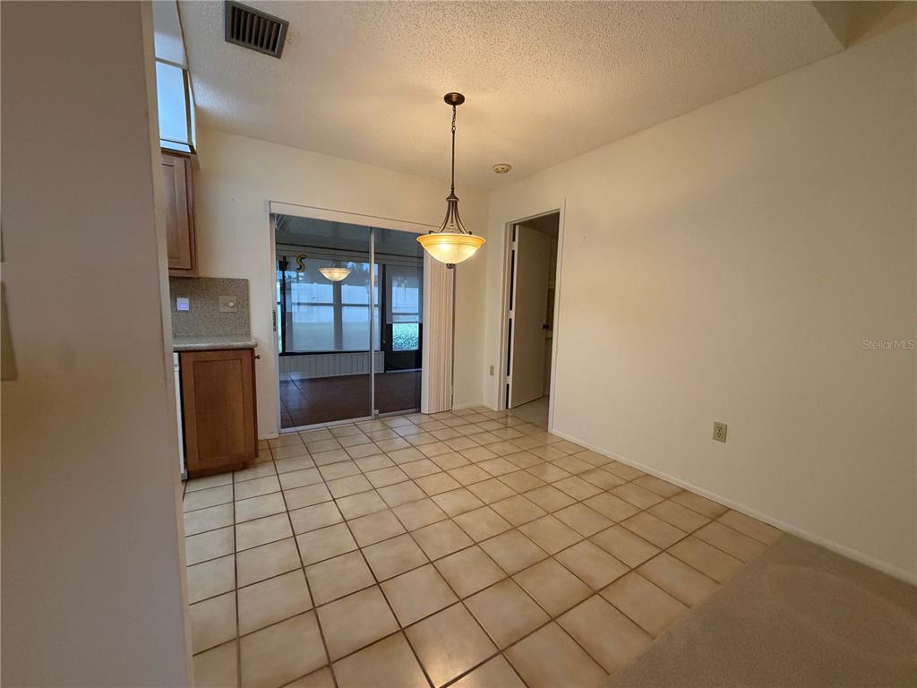 A dining area with tiled floors, a hanging light fixture, and a sliding glass door — 6736 JARVIS ROAD, SARASOTA, FL