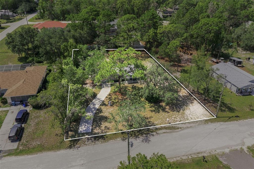 An aerial view shows a vacant, tree-covered residential lot outlined in white — 10380 GOLDEN AVENUE, WEEKI WACHEE, FL